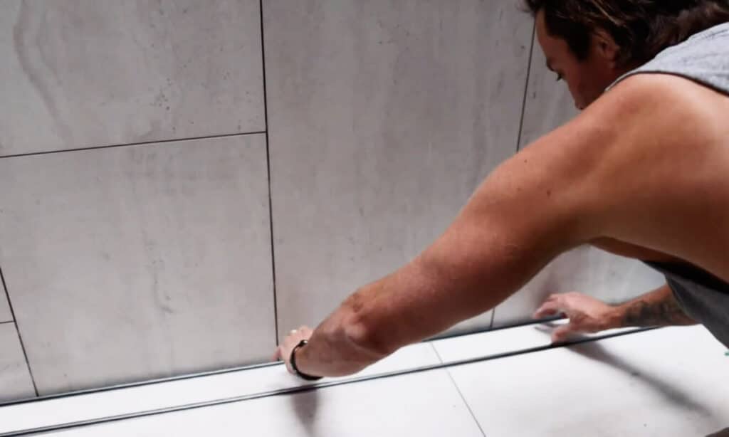 Man Installing Grate On The Bathroom Floor